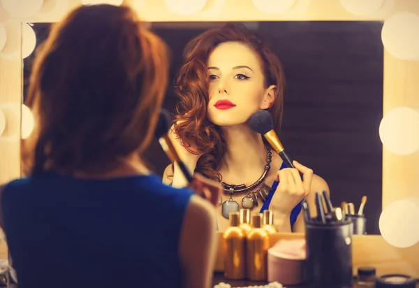 Portret van een mooie vrouw als toepassing van make-up in de buurt van een spiegel — Stockfoto