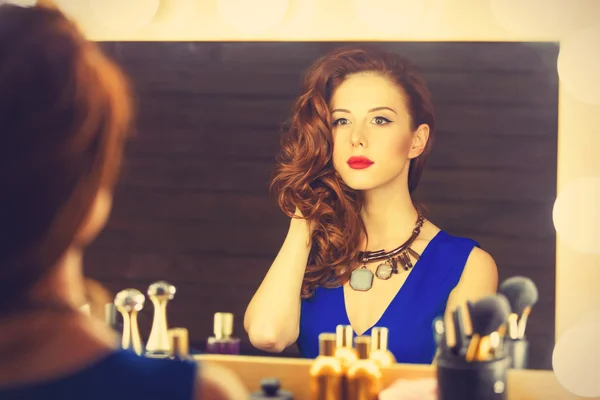 Porträtt av en vacker kvinna som tillämpa makeup nära en spegel — Stockfoto