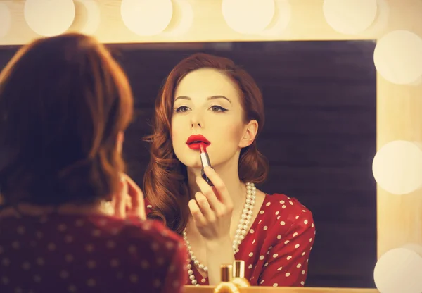 Portret van een mooie vrouw als toepassing van make-up in de buurt van een spiegel — Stockfoto