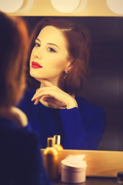 Portret van een mooie vrouw als toepassing van make-up in de buurt van een spiegel — Stockfoto