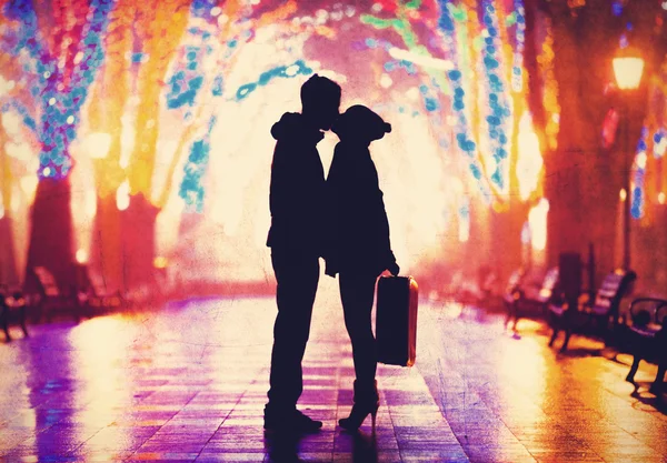 Pareja con maleta besándose en callejón nocturno . — Foto de Stock