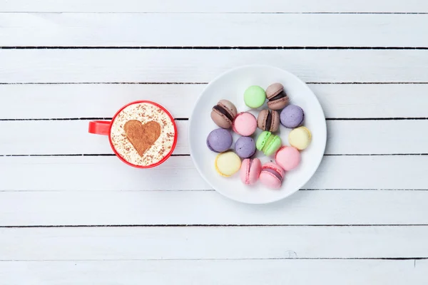 Cappuccino with heart shape symbol and macaron — Stock Photo, Image