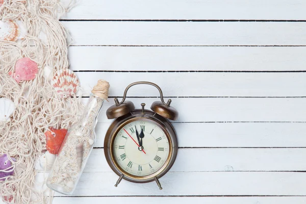 Alarm clock and net with shells and bottle — Stock Photo, Image