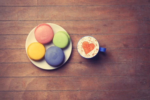 Cup and macarons on wooden background — Stock Photo, Image