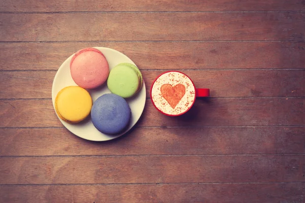 Cup och macarons på trä bakgrund — Stockfoto