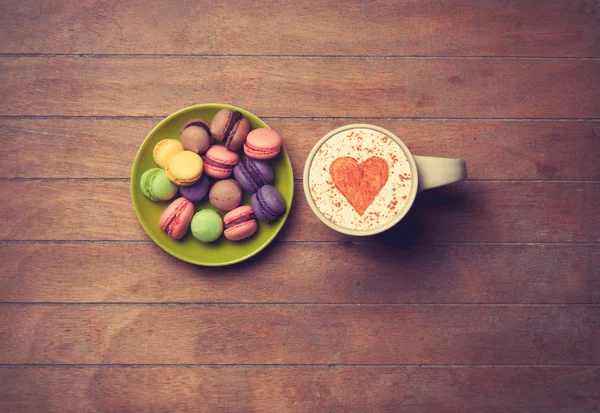 Cup and macarons on wooden background — Stock Photo, Image