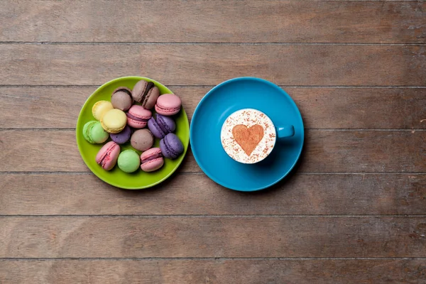 Puchar i macarons na drewniane tła — Zdjęcie stockowe