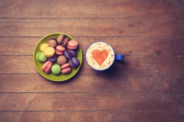 Cup and macarons on wooden background — Stock Photo, Image