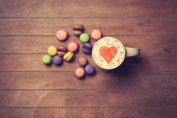 Tasse und Macarons auf Holzgrund — Stockfoto