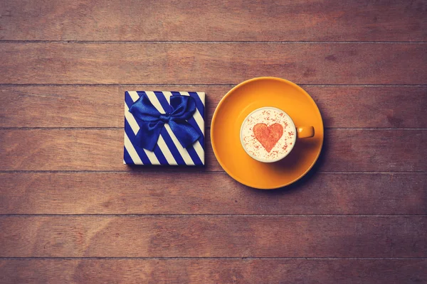 Cup and gift box on wooden background — Stock Photo, Image