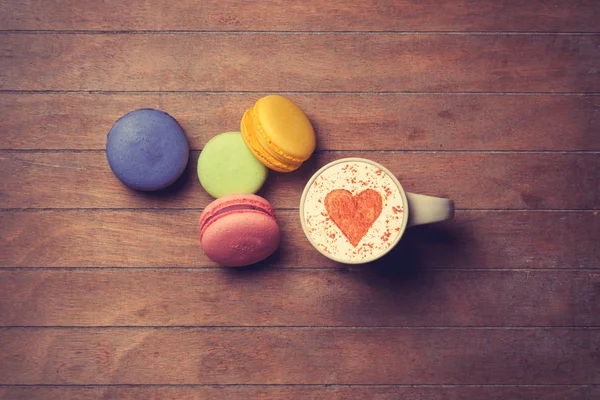 Cup och macarons på trä bakgrund — Stockfoto