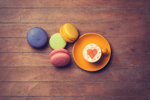 Cup and macarons on wooden background — Stock Photo, Image