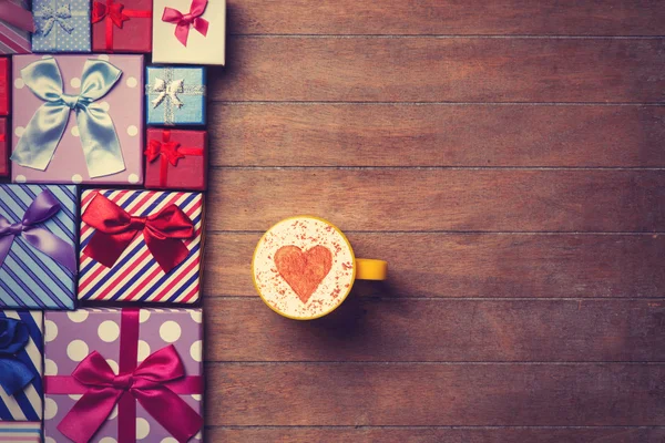 Cup and gift boxes on wooden background — Stock Photo, Image