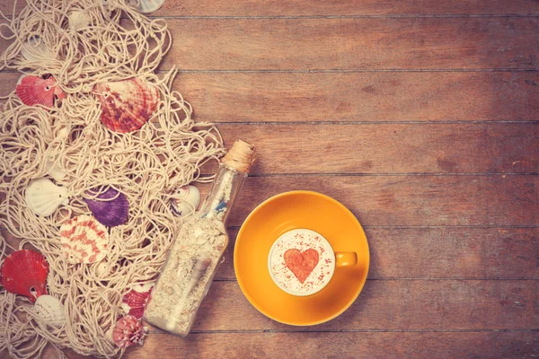 Cup and net with shells and bottle — Stock Photo, Image