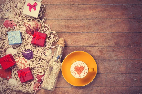 Tasse, Geschenk und Netz mit Muscheln und Flasche — Stockfoto