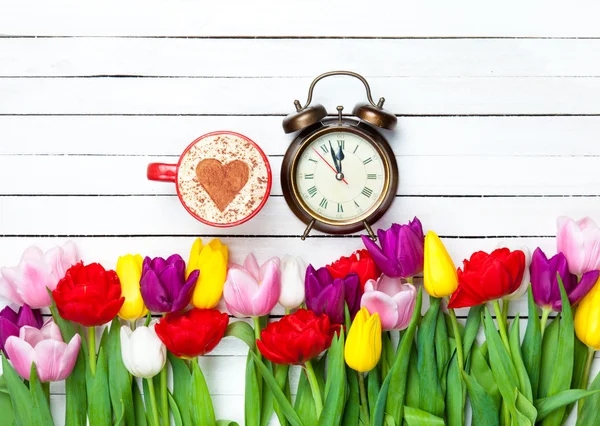 Cappuccino och klockan nära blommor — Stockfoto