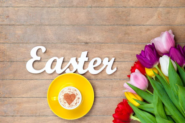 Cappuccino y palabra Pascua cerca de las flores —  Fotos de Stock