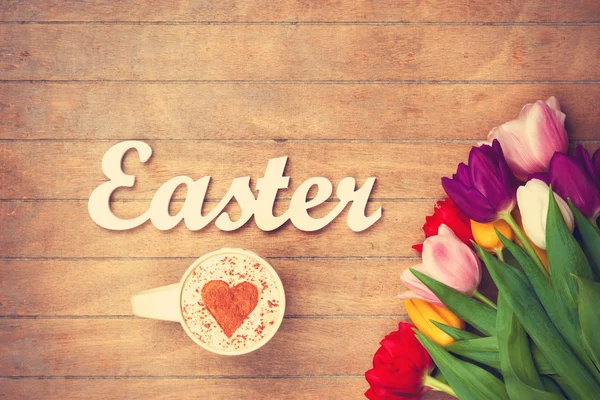 Cappuccino y palabra Pascua cerca de las flores —  Fotos de Stock