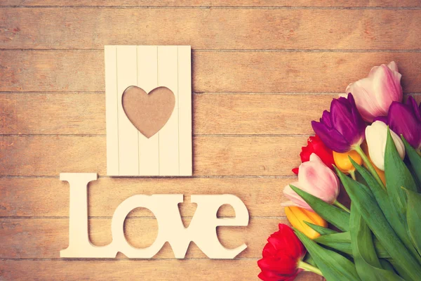 Bouquet of tulips and word Love near photo frame — Stock Photo, Image