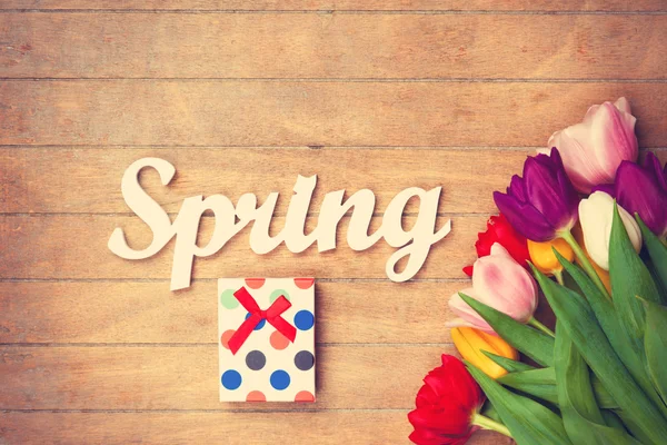 Подарочная коробка и слово Весна возле цветов — стоковое фото