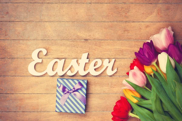 Geschenk-Box und Wort Ostern in der Nähe von Blumen — Stockfoto