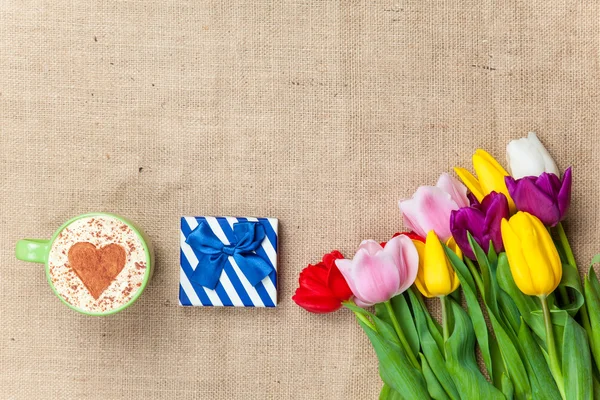 Cappuccino and gift box near flowers — Stock Photo, Image