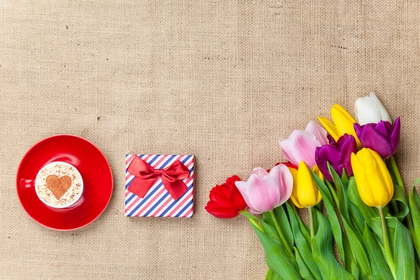 Cappuccino and gift box near flowers — Stock Photo, Image