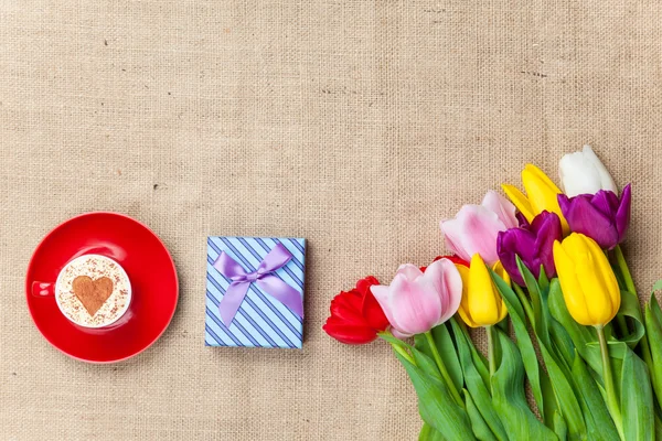 Cappuccino och present box nära blommor — Stockfoto