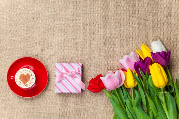 Capuchino y caja de regalo cerca de flores — Foto de Stock