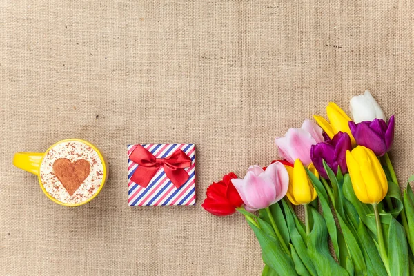 Cappuccino and gift box near flowers — Stock Photo, Image