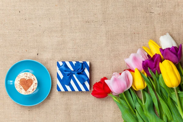 Cappuccino and gift box near flowers — Stock Photo, Image