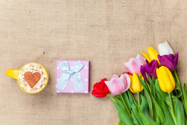 Cappuccino and gift box near flowers — Stock Photo, Image