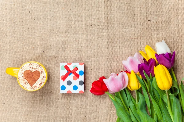 Capuchino y caja de regalo cerca de flores — Foto de Stock