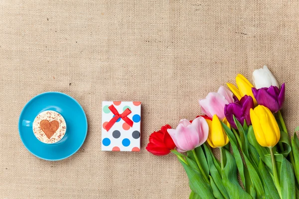 Cappuccino and gift box near flowers — Stock Photo, Image