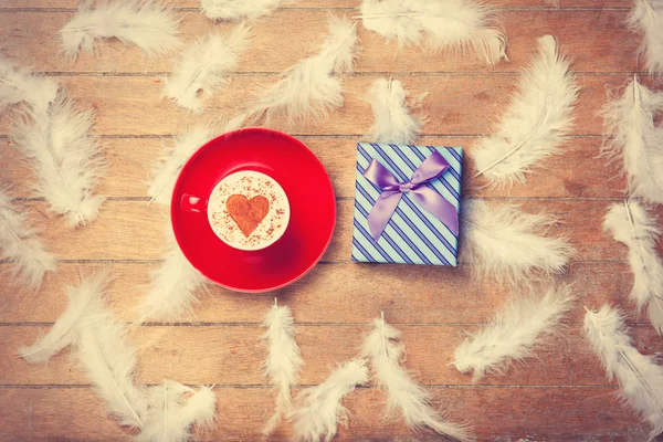 Caffè e piume con regalo su sfondo di legno . — Foto Stock