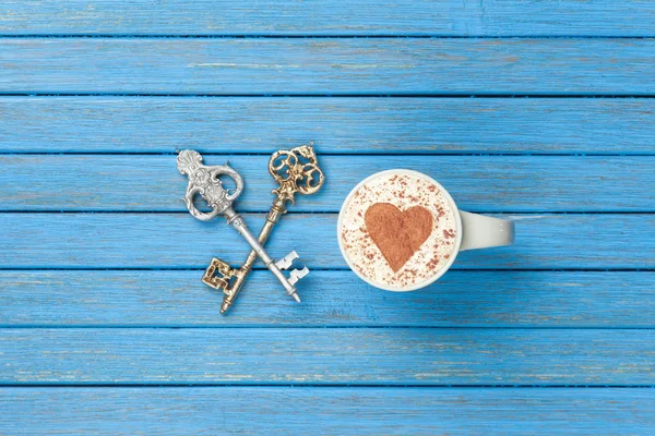 Cup of Cappuccino with heart shape symbol and two keys — Stock Photo, Image