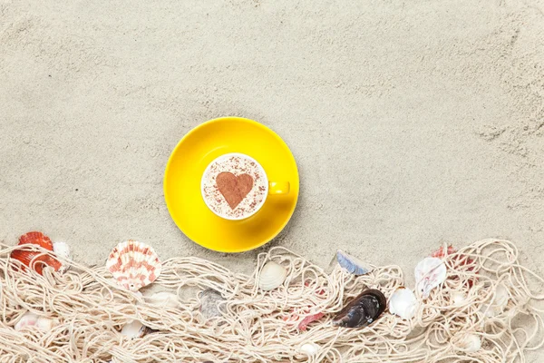 Cup och nätet med skal på sand — Stockfoto