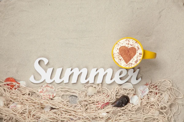 Cup, word Summer and net with shells on sand — Stock Photo, Image