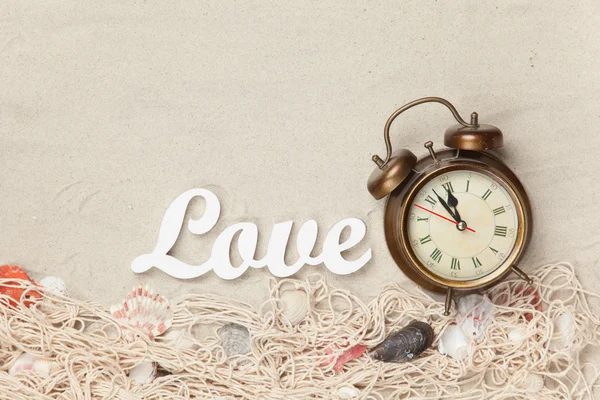 Alarm clock and word Love, net with shells — Stock Photo, Image