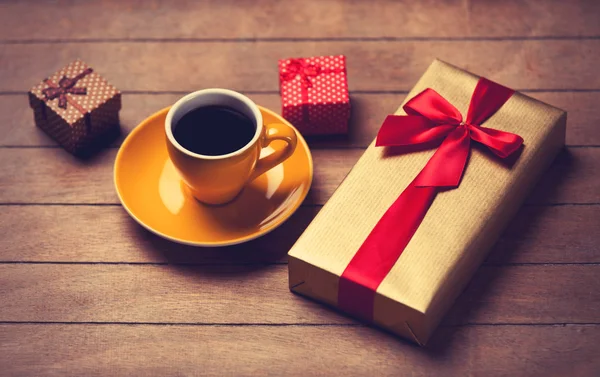 Taza de café y cajas de regalo en una mesa de madera . — Foto de Stock