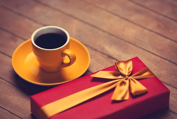 Filiżankę kawy i prezent pudełko na drewnianym stołem. — Zdjęcie stockowe