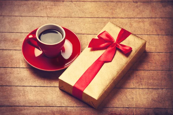 Cup of coffee and gift box on a wooden table. — Stock Photo, Image