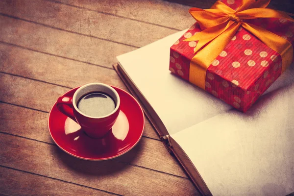 Cup of coffee and gift box with book on a wooden table — Stock Photo, Image