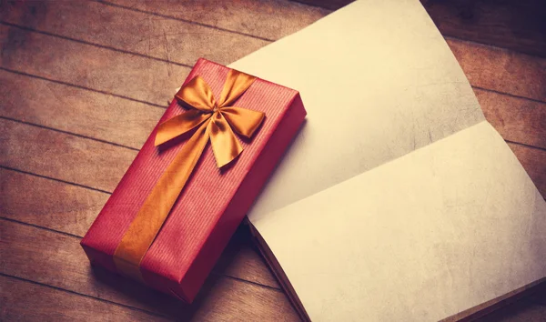 Libro abierto y caja de regalo en una mesa de madera . — Foto de Stock