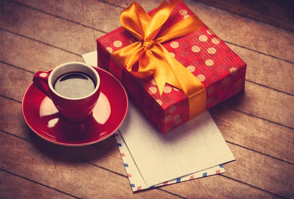 Tasse Kaffee und Geschenkbox mit Umschlägen auf einem Holztisch. — Stockfoto