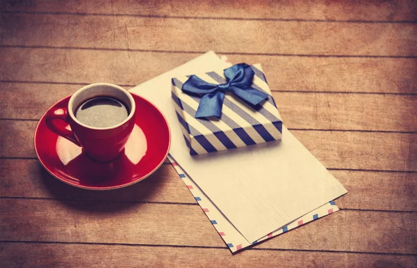 Filiżankę kawy i prezent pudełko z koperty na drewnianym stołem. — Zdjęcie stockowe