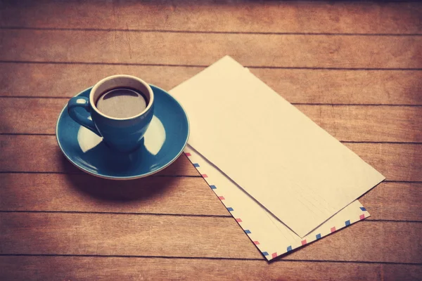 Xícara de café e emvelopes em uma mesa de madeira . — Fotografia de Stock