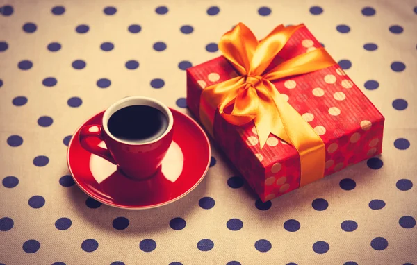 Cup of coffee and gift box on a polka dot background. — Stock Photo, Image