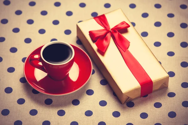 Cup of coffee and gift box on a polka dot background. — Stock Photo, Image