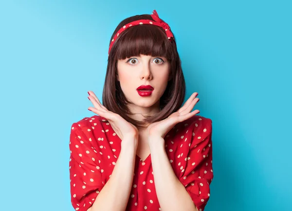 Brunette meisje in een rode jurk op blauwe achtergrond — Stockfoto